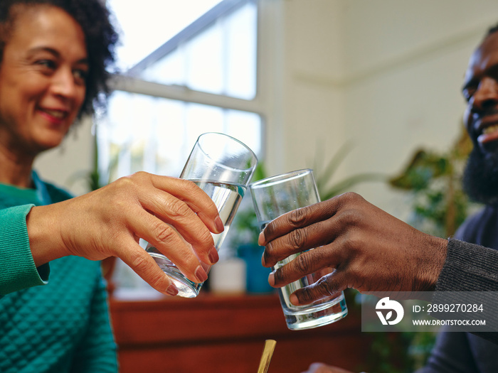 Couple raising toast with glasses of water