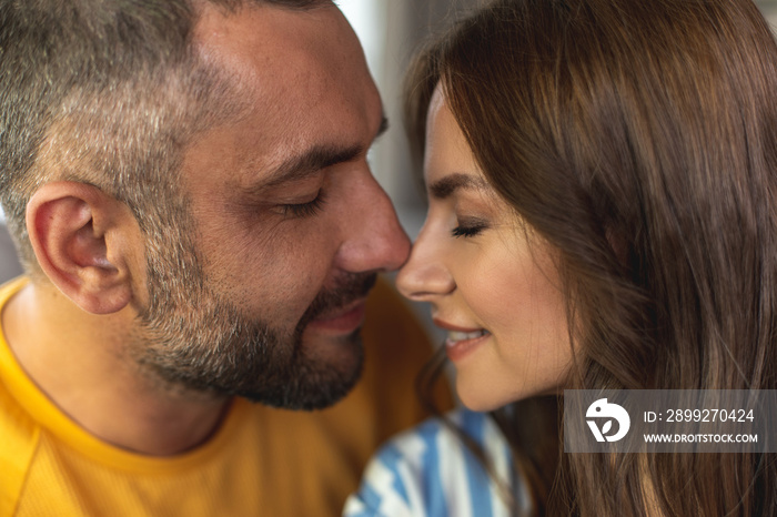 Close up of happy man and woman making romantic photo with closed eyes while touching each other noses