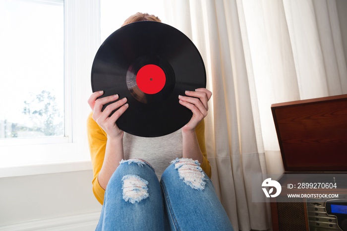 Woman hiding her face with vinyl record