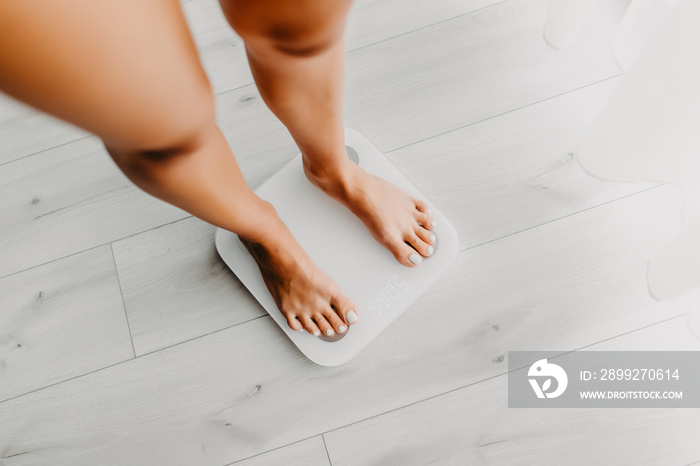 Feet of young woman on weighting scale at home