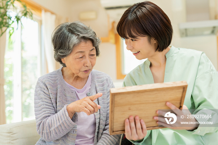 孫と写真を見るシニア女性