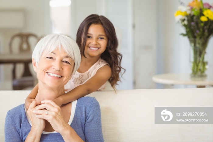 Smiling girl embracing her grandmother at home