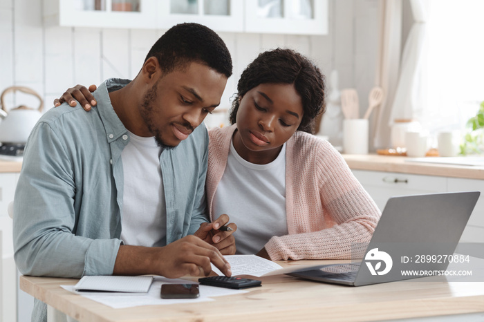 Portraif Of Young African Couple Sitting At Table In Kitchen, Reading Documents