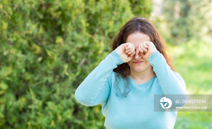 Woman suffering itching scratching eyes in a park