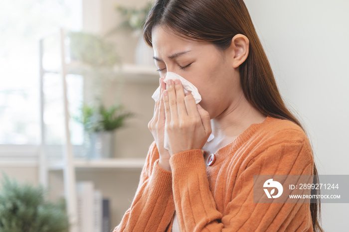 Close-up woman Asian woman sneezing from allergy on tissue paper at home.