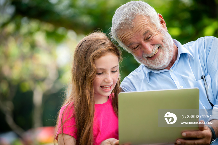 Happy family using laptop computer together in the garden park in summer. Kid education and family activities concept.