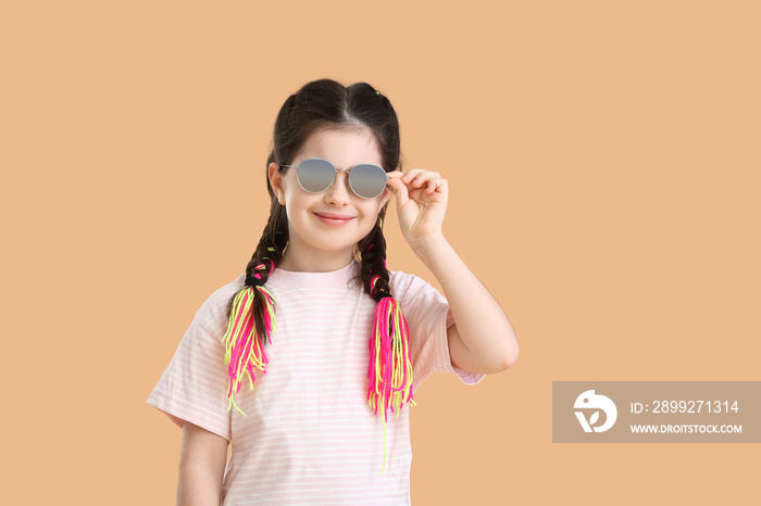 Cute little girl wearing sunglasses on color background