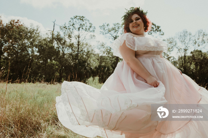 plus size woman plays with dress in field