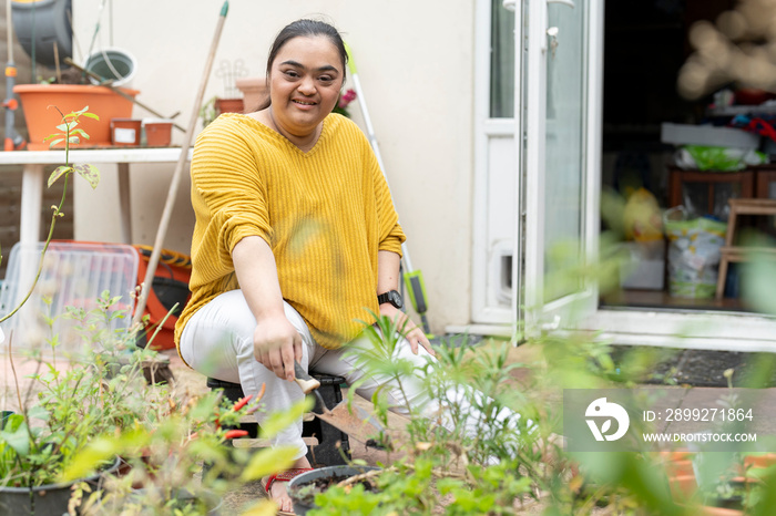 Portrait of young woman with down syndrome planting flowers in garden