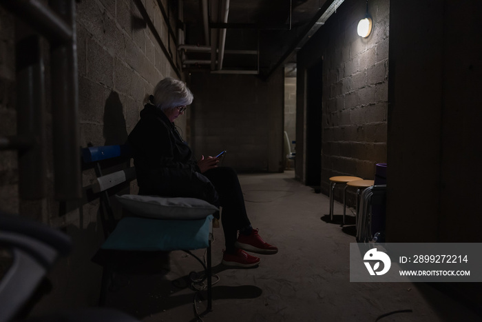 Woman is sitting on a bench and reading a war news in a bombproof shelter