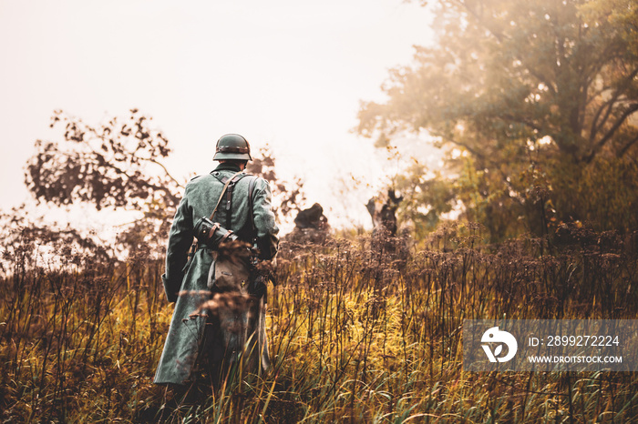 Single Re-enactor Dressed As German Wehrmacht Infantry Soldier In World War II Walking In Patrol Through Autumn Forest. WWII WW2 Times