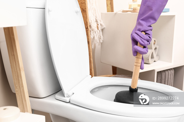 Man using plunger to unclog a toilet bowl