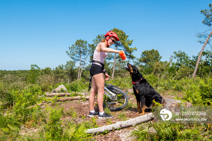 pretty young woman giving her dog a drink on a walk