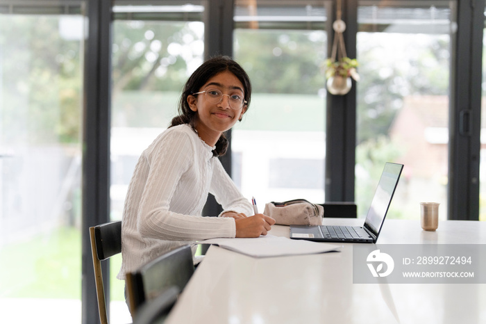 Girl doing homework and using laptop in living room