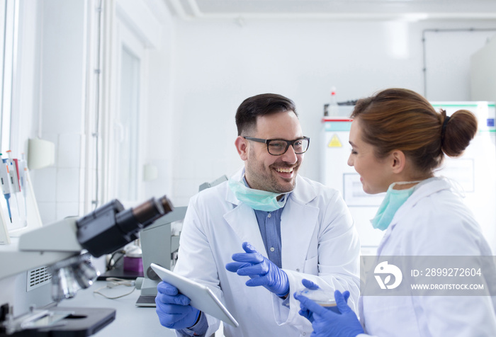 Two smiling doctors scientists discussing test results in laboratory