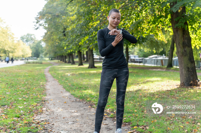 Athletic woman checking smart watch in park