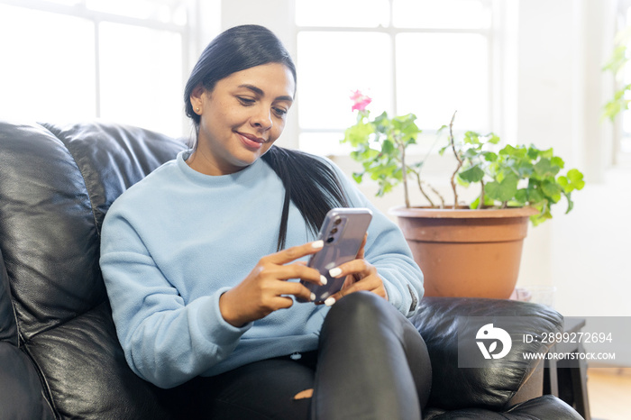 Woman sitting on sofa and using smartphone