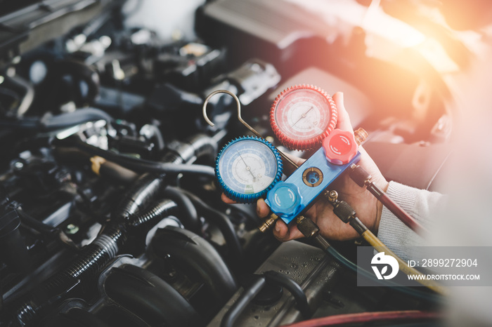 Hand of young mechanic with Gauges Set, Check the pressure and leak. Servicing car air conditioner