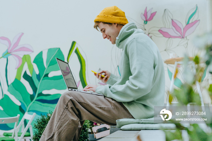 Freelancer young man working on laptop sitting on the stairs