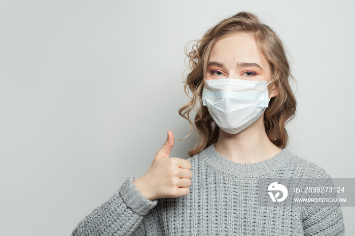 Happy woman wearing a face mask showing thumb up. Virus protection concept