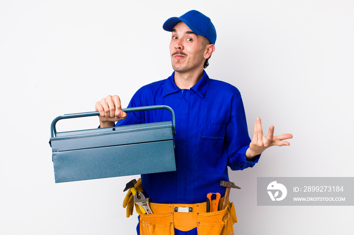 young hispanic plumber shrugging, feeling confused and uncertain. toolbox concept