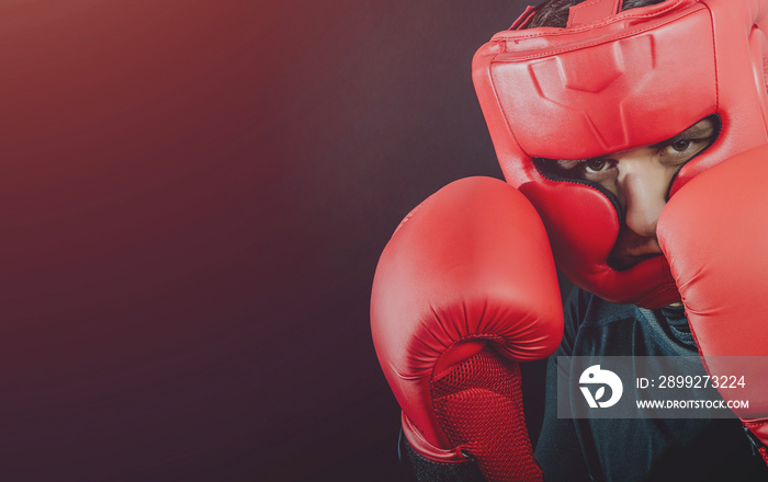 Boxer in boxing gloves and boxing helmet on a dark black background. Concept of sport and active leisure. Practicing martial arts. Playing sports, taking care of figure, fight and self-defense.