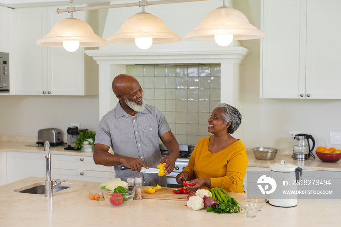 Senior african american couple cooking together in kitchen smiling