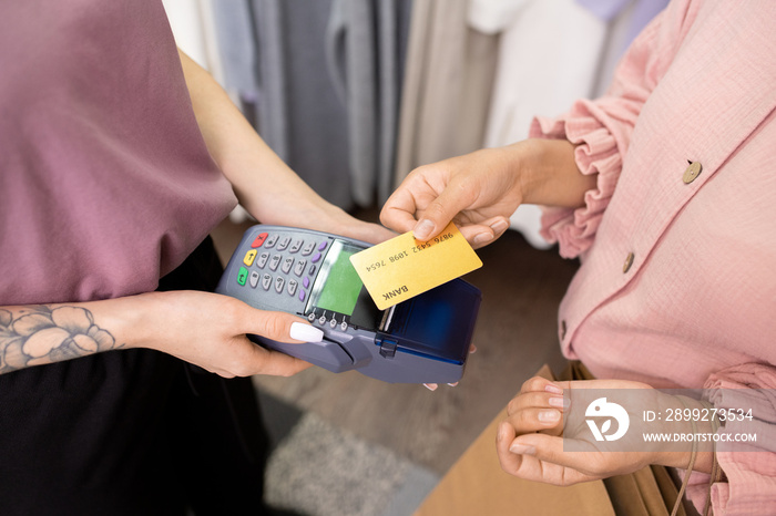 Close-up of young woman paying with credit card for her purchases in the shop