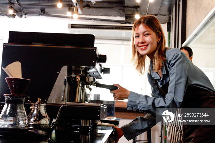 Portrait of a happy Asian woman working in a coffee shop. Successful small business owner in casual brown apron making coffee. Cafe owner and small business concept