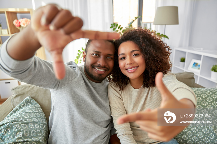 leisure and people concept - happy african american couple making selfie frame gesture at home