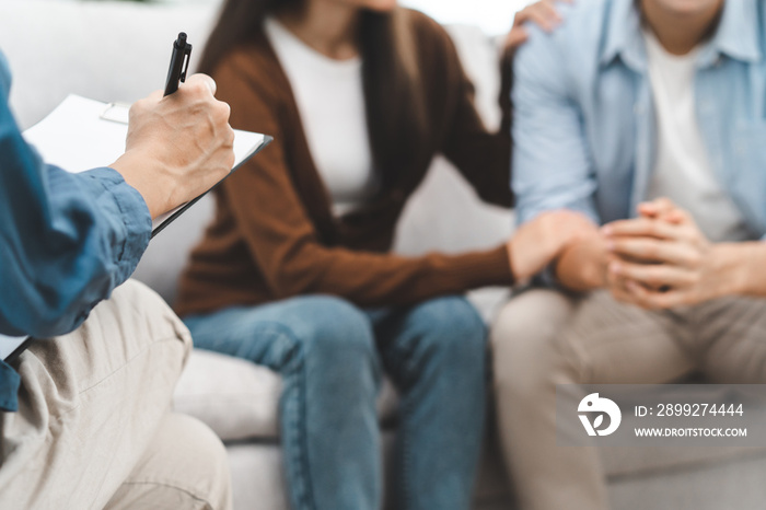 couple relationship therapy with a counselor. Close Up hands of the psychologist take notes on a clipboard during a conversation with clients to find problems and solution.