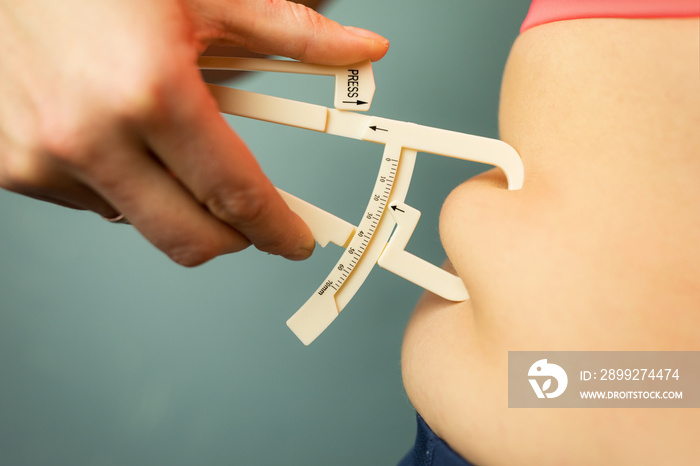 Woman measuring her body fat with caliper