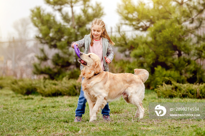 Little girl with golden retriever dog outside