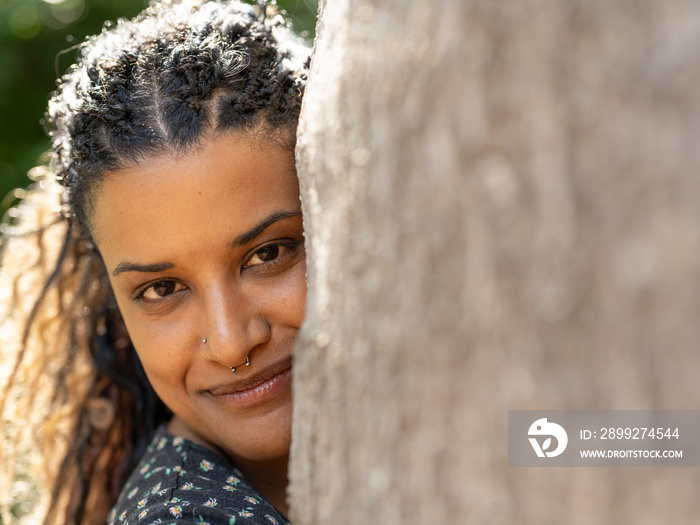 Portrait of smiling woman hugging tree