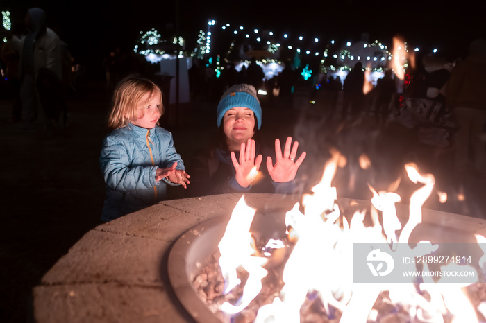 Mother and daughter warming their hands at a fire pit