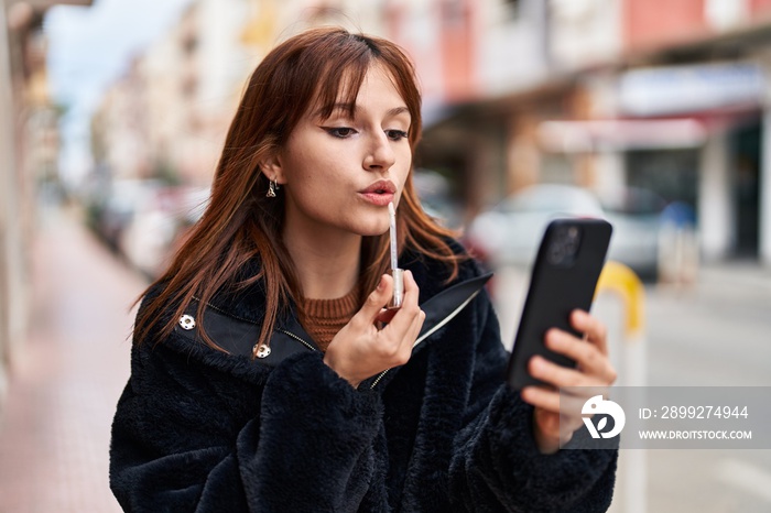 Young woman makeup lips holding smartphone at street