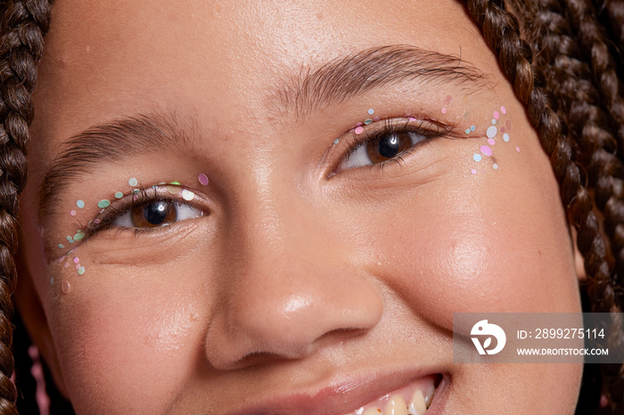 Close-up of smiling girl with decorative stickers on face