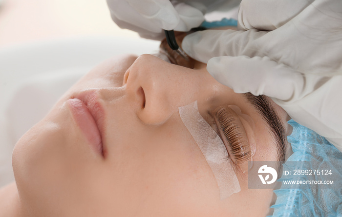 Young woman undergoing procedure of eyelashes lamination in beauty salon, closeup