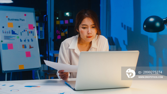 Freelance Asia women using laptop hard work in living room at house. Working from home overload at night, remotely work, self isolation, social distancing, quarantine for corona virus prevention.