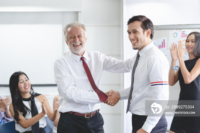 Young businessman promoted. Boss shaking hands with employee celebration for new position.