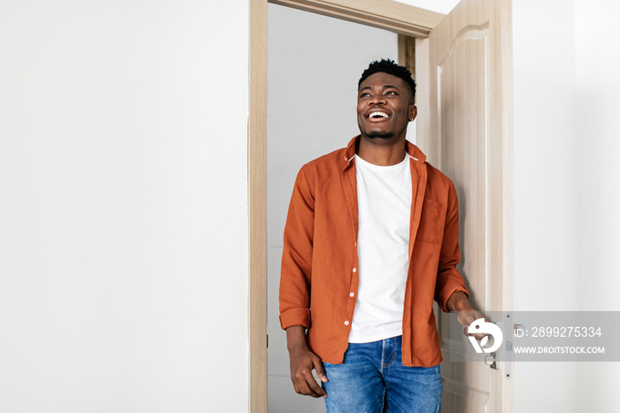 Cheerful Black Guy Entering New Home Opening The Door