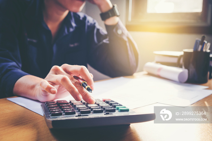 Businessman’s hands with calculator at the office and Financial data analyzing counting on wood desk