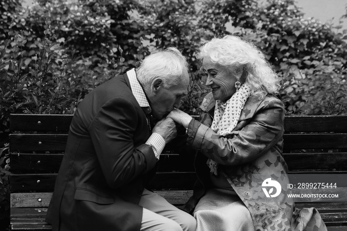 Elderly man kisses hands of the elderly woman. Black and White.