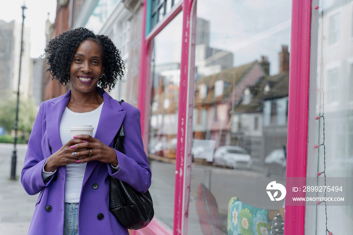 Portrait of smiling woman standing with disposable cup in city