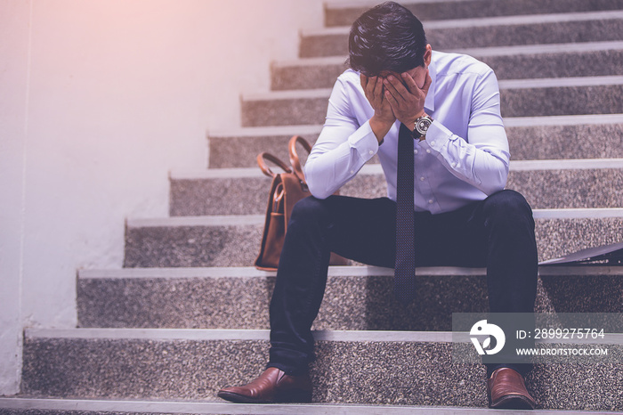 stressed businessman with headache sitting at stairway. disappointed for job search