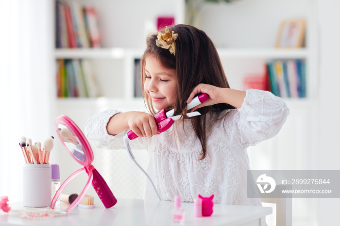 beautiful young girl, kid curling the hair with iron curler and toy beauty set