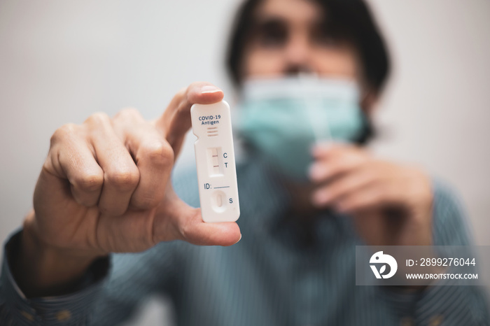 A man holds the positive antigen rapid test kit while inserting the rod into his nose.COVID19, omicron.