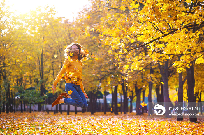 girl in a park throws yellow leaves