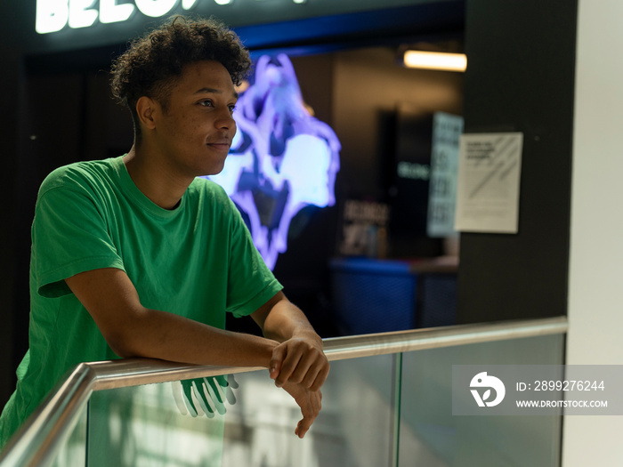 Young man looking away while leaning on glass railing