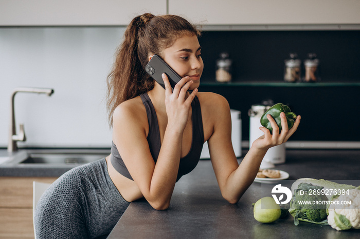 Sporty woman at kitchen using mobile phone